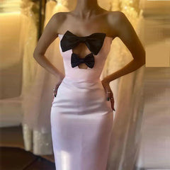 White strapless dress with black bow details on a blurred background