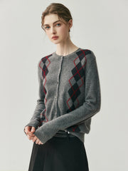 Woman wearing a gray cardigan with red and black diamond pattern on a light gray background