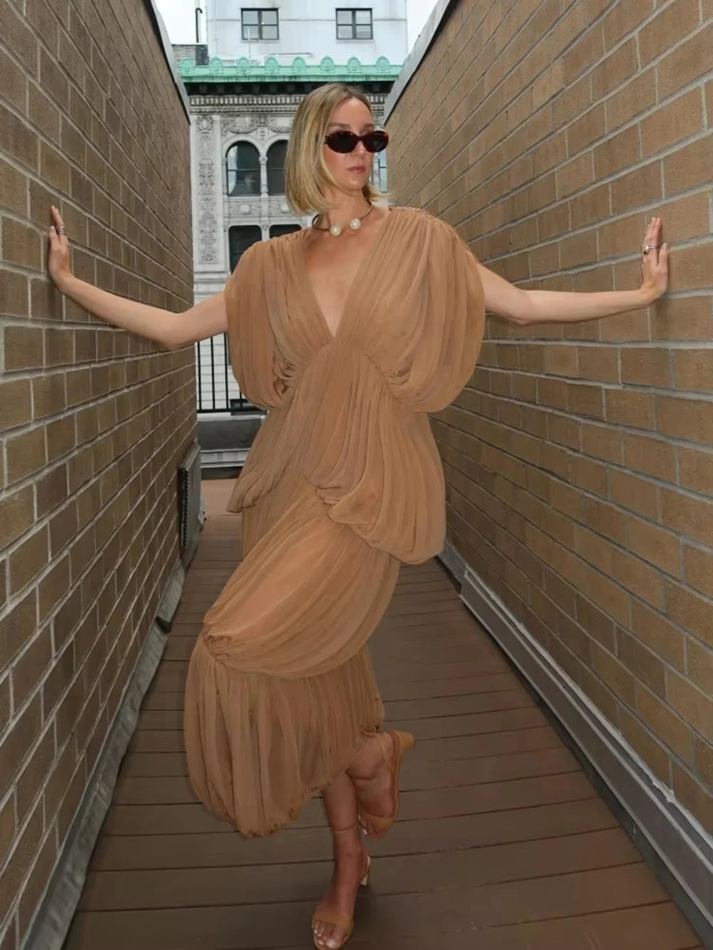 Gauze drape v-neck dress on model in narrow alleyway with arms outstretched