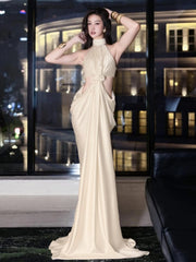Woman in a white evening gown standing in front of a window with city lights.