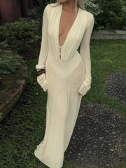 Woman wearing a long-sleeve, off-white dress with a plunging neckline in an outdoor setting.