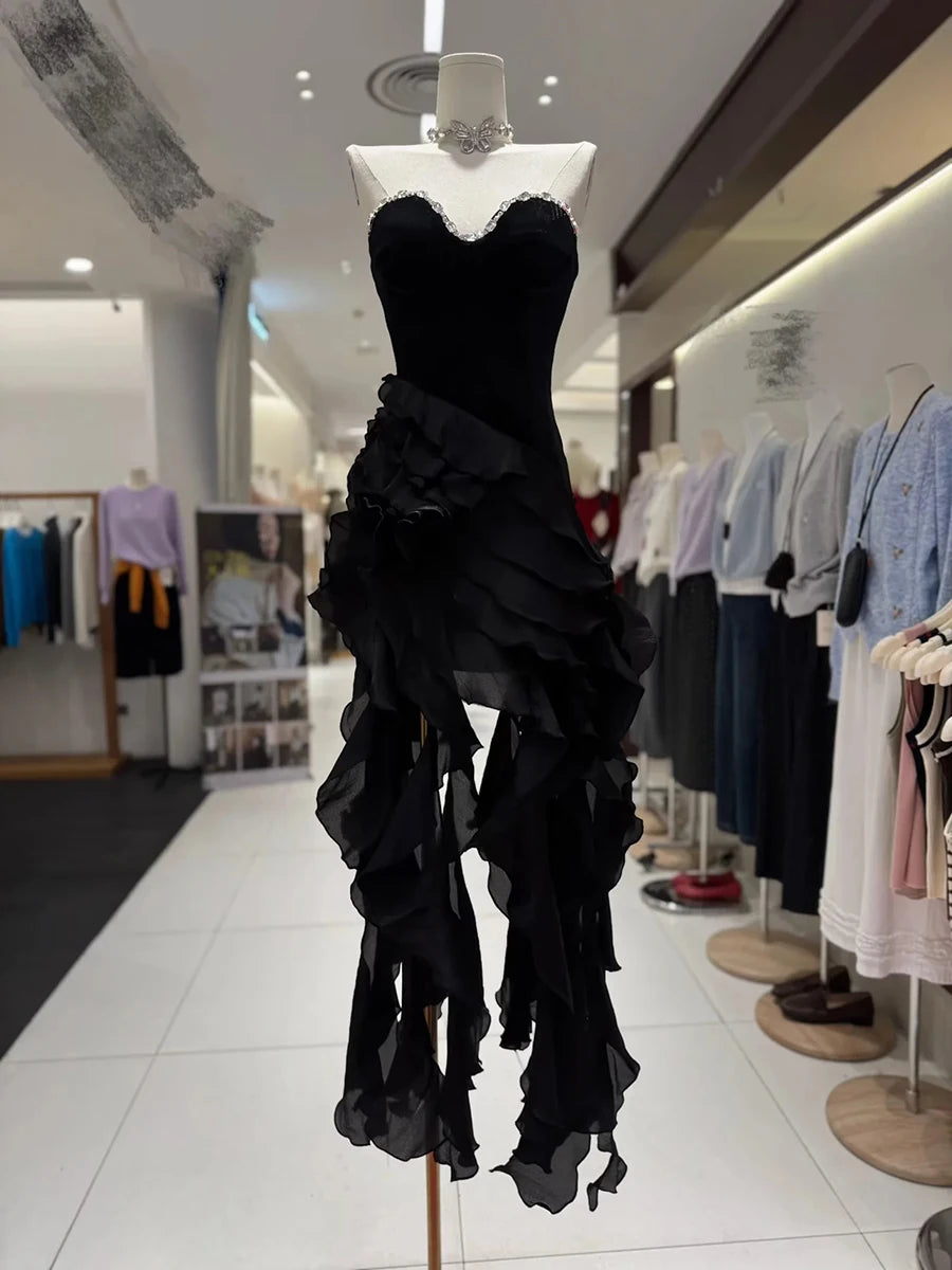 Black ruffled dress on a mannequin in a store setting with other clothing in the background.