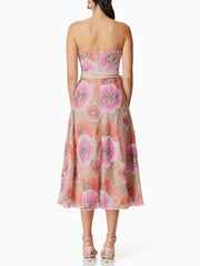 Woman wearing a strapless floral dress with pink and orange flowers on a white background