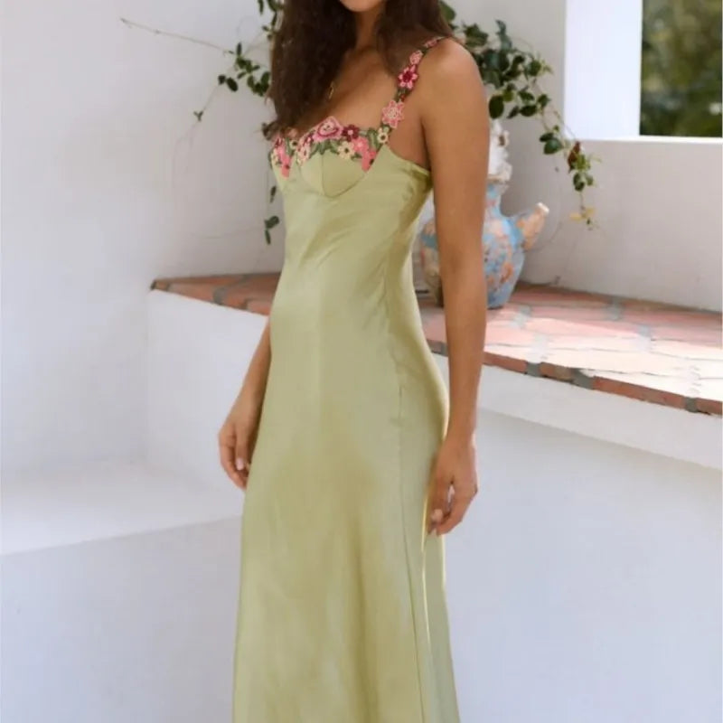 Woman wearing a light green satin slip dress with floral embroidered straps