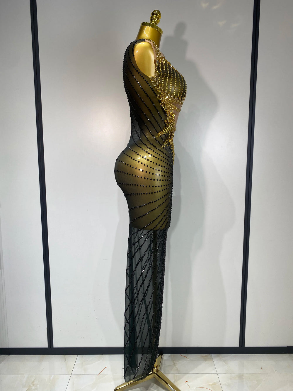 Mannequin wearing a black and gold dress against a white wall.