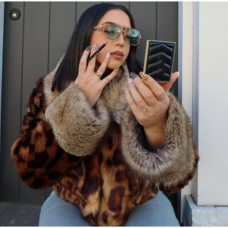 Person wearing a leopard print coat and fur-lined hood, holding a compact mirror.