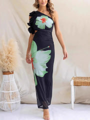 Woman wearing a black one-shoulder dress with floral designs in a minimal indoor setting.
