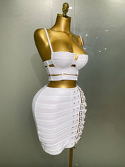 Mannequin wearing a white outfit with gold accents on a plain background