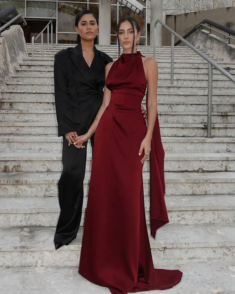 Two women standing on a staircase, one in a black outfit and the other in a burgundy dress.