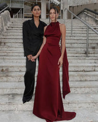 Two women standing on a staircase, one in a black outfit and the other in a burgundy dress.