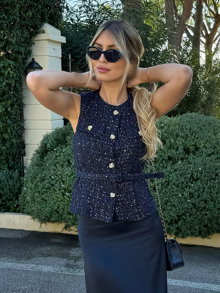 Woman wearing a dark blue sparkly top and black skirt outdoors.