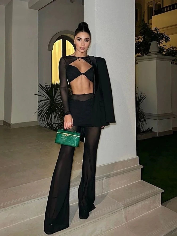 Woman in a black outfit holding a green handbag on steps.