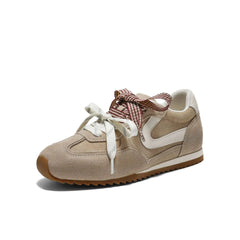 Beige suede low-top sneaker with white accent and decorative laces.