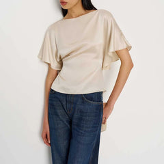 Woman wearing a beige top and blue jeans on a white background