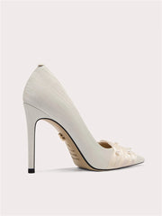 White high-heeled shoe with decorative elements on a light gray background