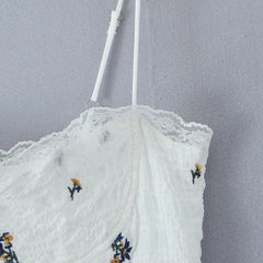 White lace garment with floral embroidery on a gray background