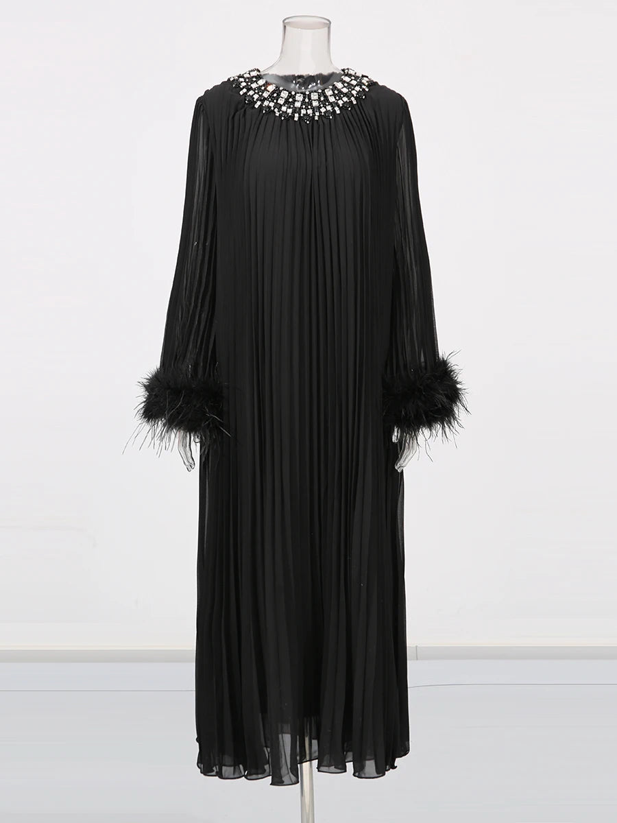 Black dress with feathered sleeves on a mannequin against a white background