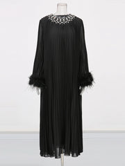 Black dress with feathered sleeves on a mannequin against a white background