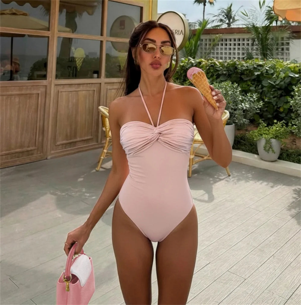 Model wearing a pink ruched bandeau swimsuit outdoors