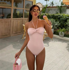 Model wearing a pink ruched bandeau swimsuit outdoors