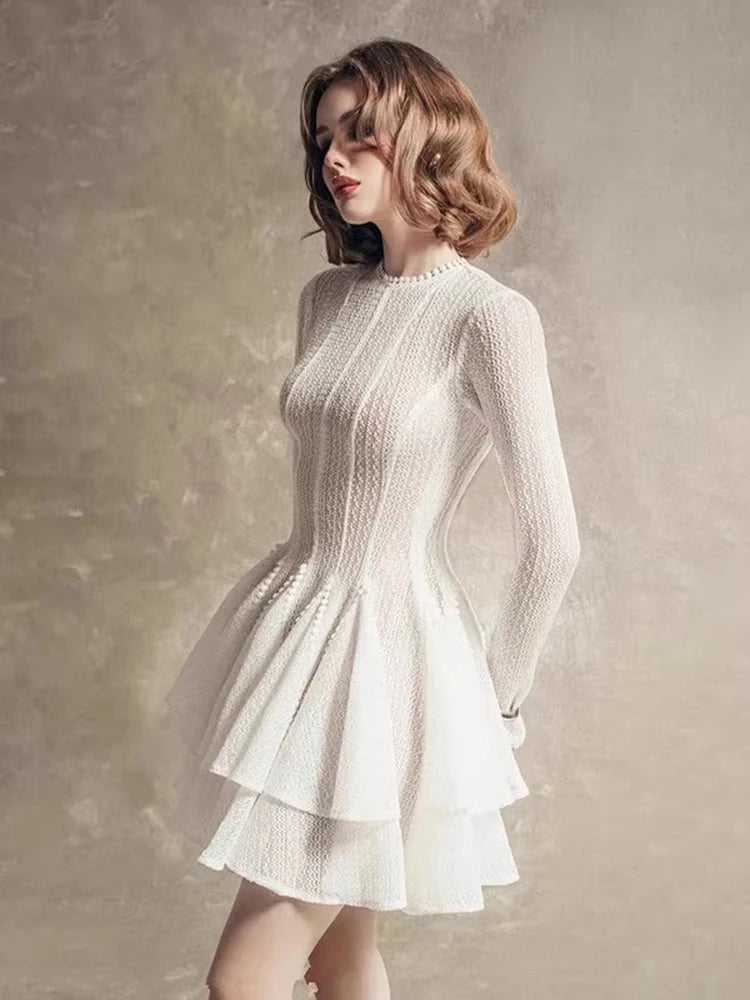 Woman wearing a white knit dress against a textured beige background