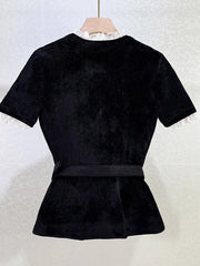 Black peplum top on a hanger against a white background