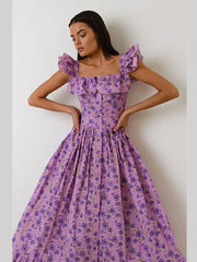 Woman wearing a purple floral dress against a plain background