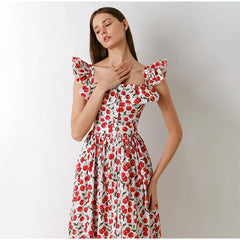 Woman wearing a floral dress with red and white pattern on a plain background