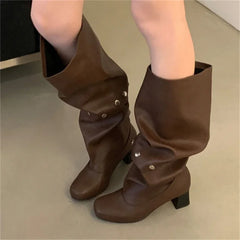 Brown knee-high boots worn by a person on a neutral background