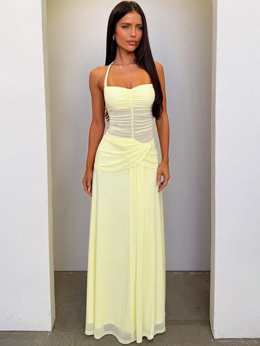 Woman wearing a light yellow evening gown against a plain background