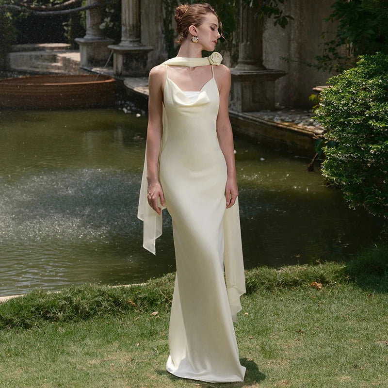 Woman in a white dress standing in a garden with a fountain in the background