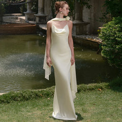 Woman in a white dress standing in a garden with a fountain in the background