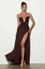 Woman wearing a strapless brown evening gown with a high slit on a white background