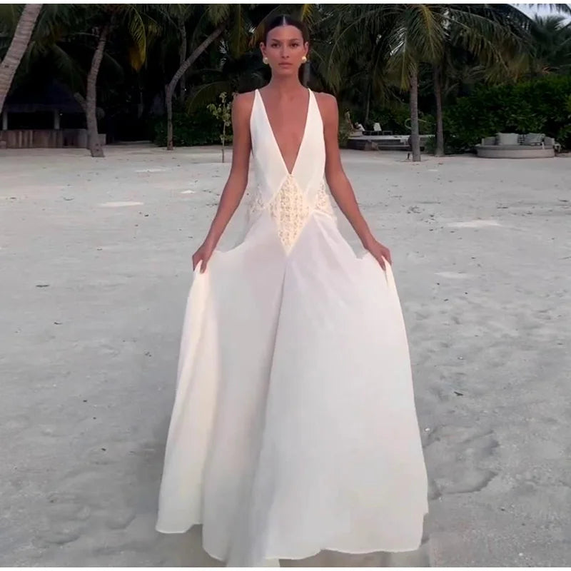 Woman in a white dress standing on a sandy beach with palm trees in the background