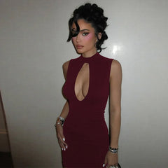 Woman wearing a burgundy dress with a cut-out design against a plain background