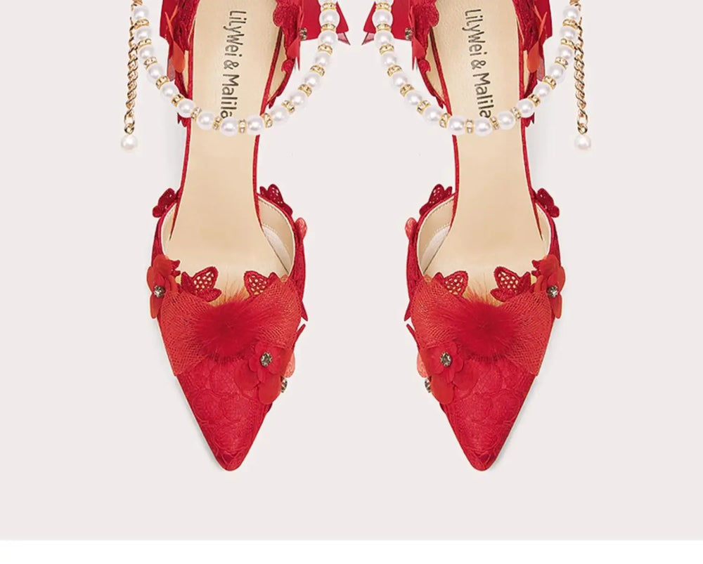 Red high-heeled shoes with floral details and pearl straps on a white background