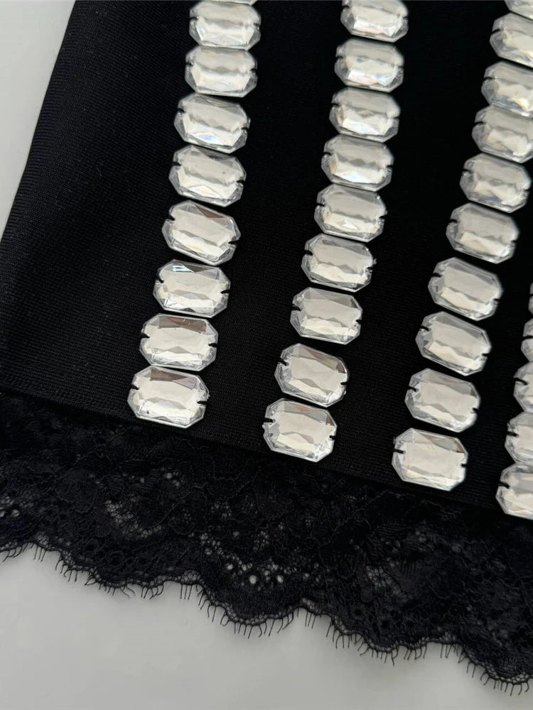 Black lace fabric with silver beaded trim on a white background