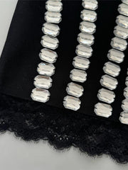 Black lace fabric with silver beaded trim on a white background