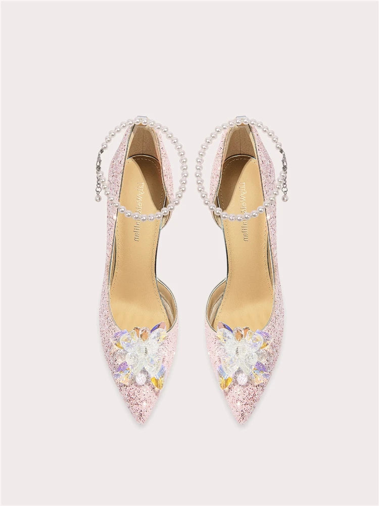 Pair of embellished high-heeled shoes on a light pink background