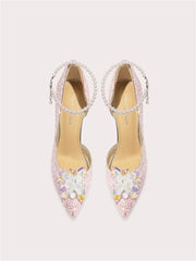 Pair of embellished high-heeled shoes on a light pink background
