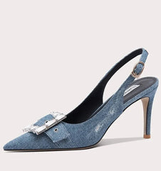 Blue denim high-heeled shoe with a decorative buckle on a white background