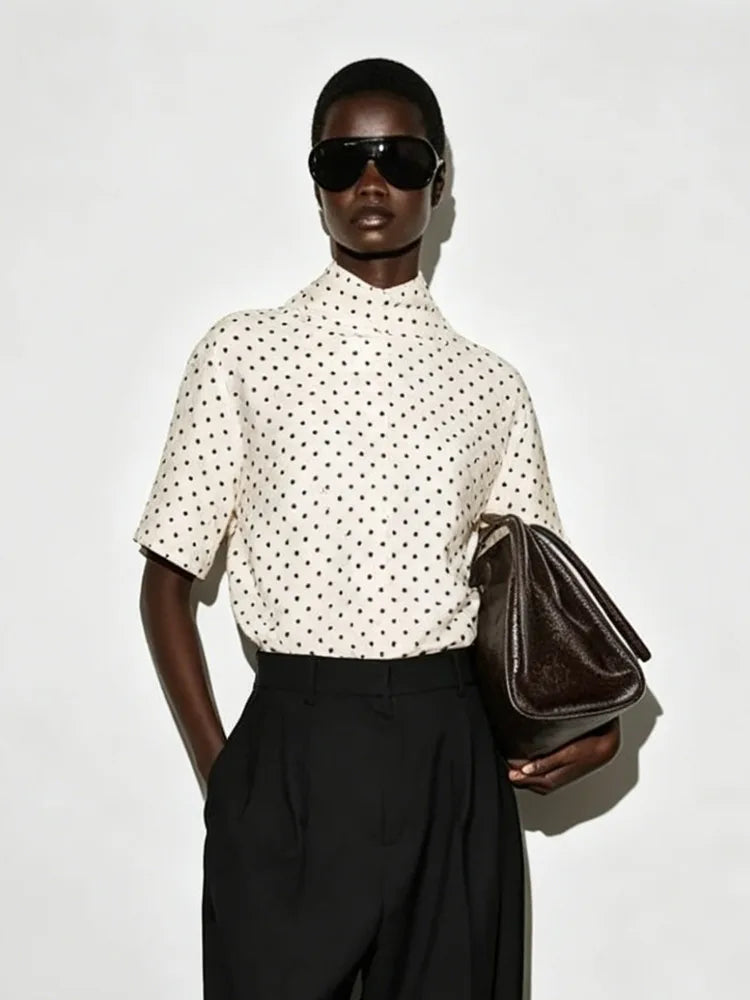 Polka dot mock neck short sleeve top styled with sunglasses and handbag