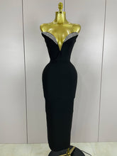 Black evening gown with beaded neckline on a mannequin against a plain background