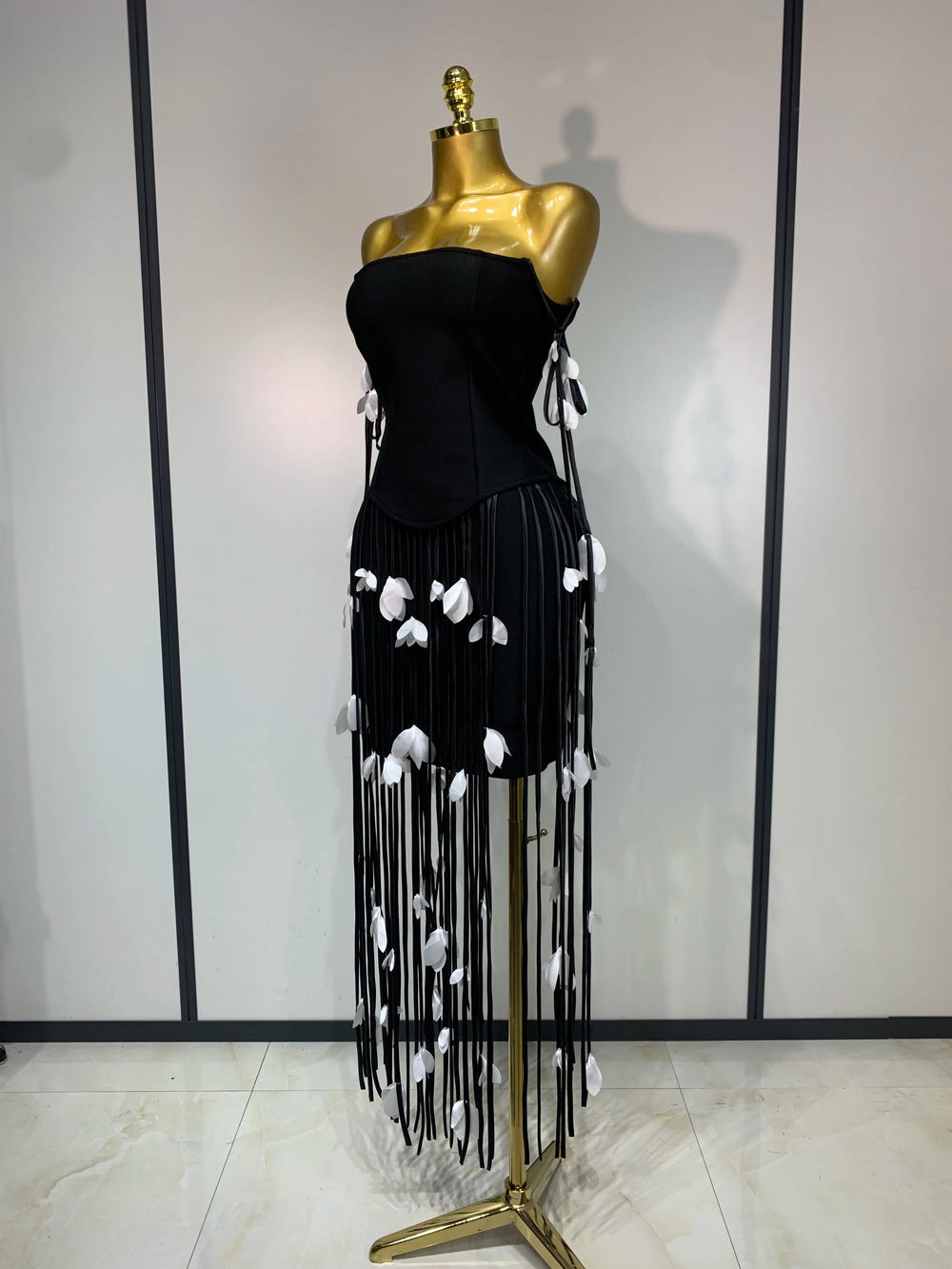 Side view of black strapless bodycon mini dress with tassel trim