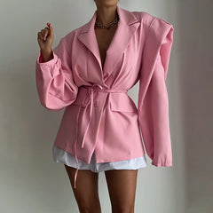 Pink blazer worn by a person on a plain background