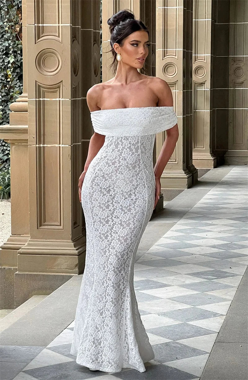 Woman in a white lace off-shoulder gown standing in front of classical architecture.