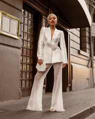 Woman in a stylish white outfit standing on a city street.