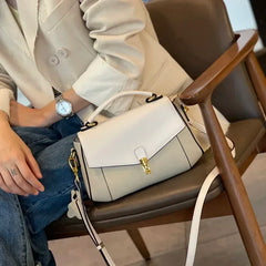Person sitting on a chair with a white handbag on their lap