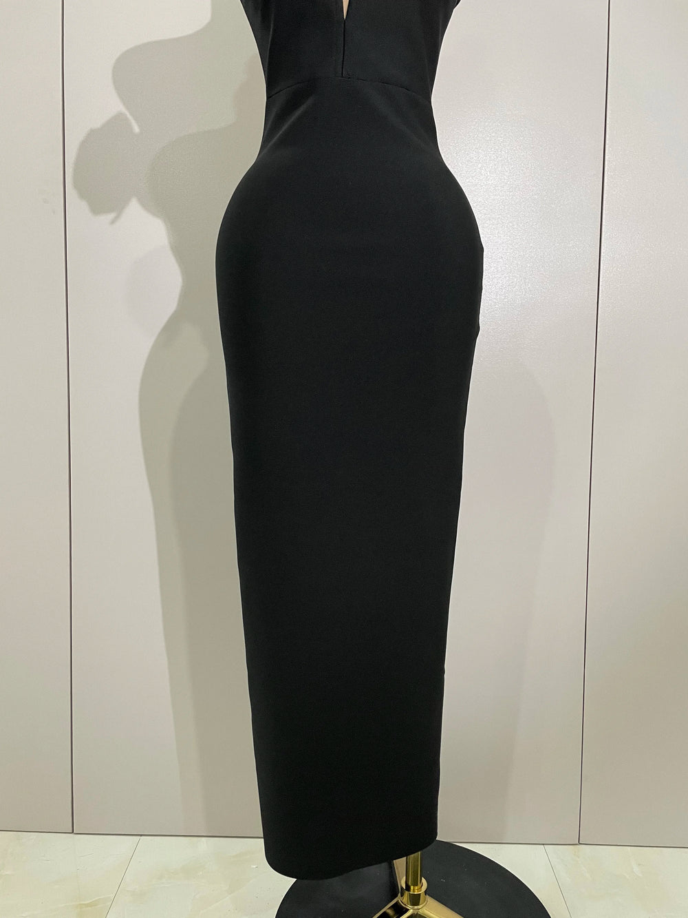 Black dress on a mannequin against a plain background