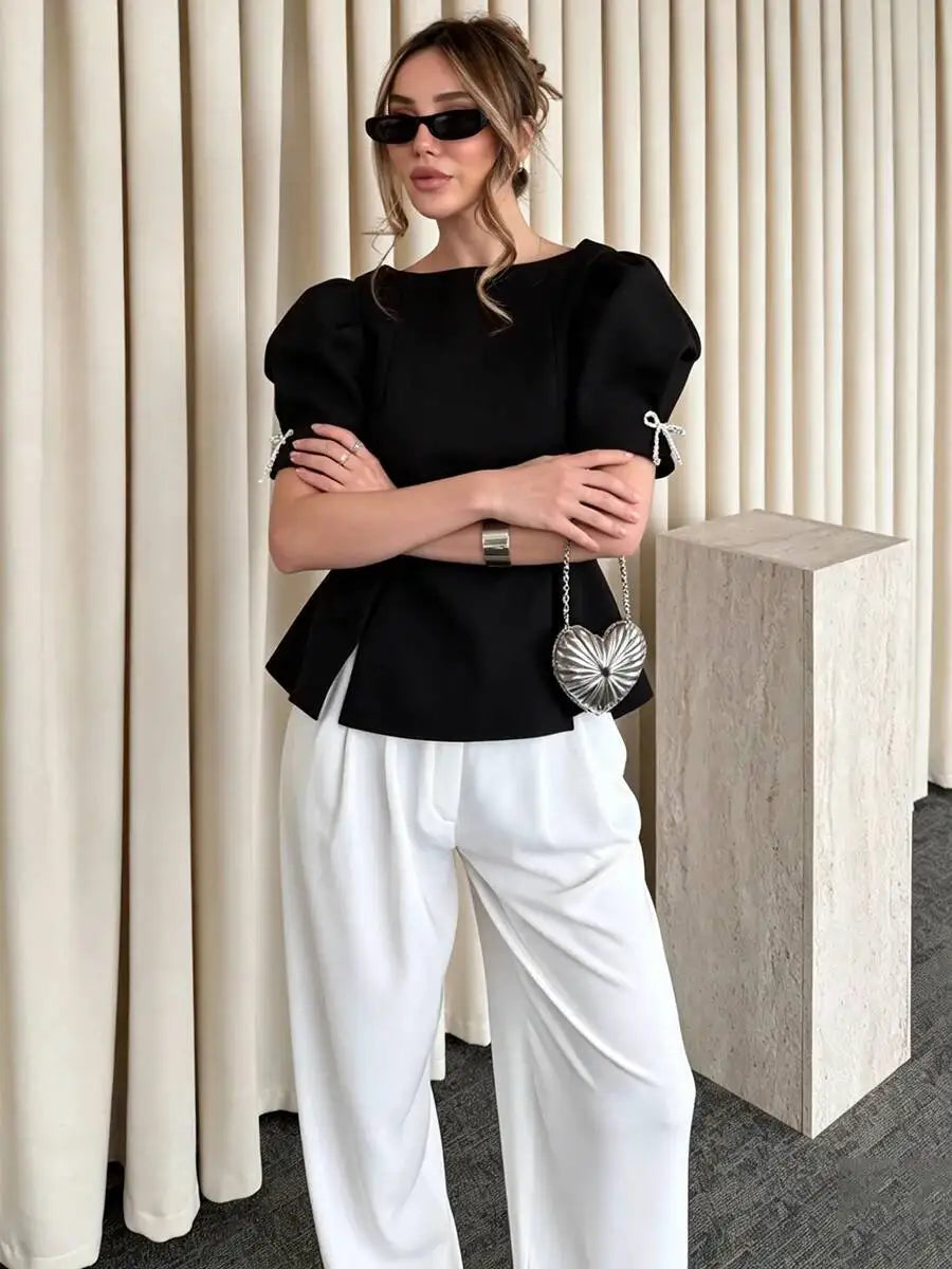 Detail of bow on sleeve of black peplum blouse
